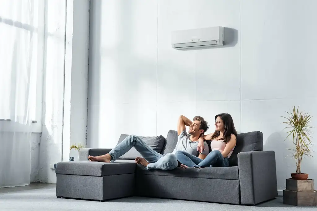 Hombre y mujer sentados en el sofa de su casa con su aire acondicionado